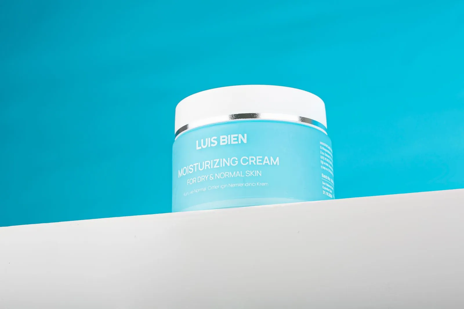 Product photo of Luis Bien moisturizing cream jar on a blue backdrop.